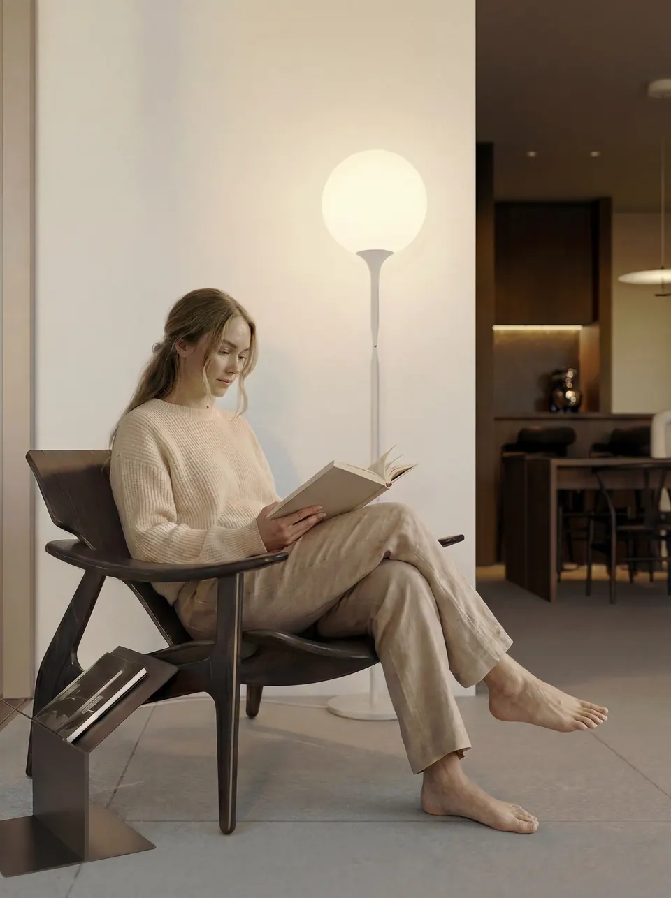 Una mujer lee en un sillón, con la cocina al fondo